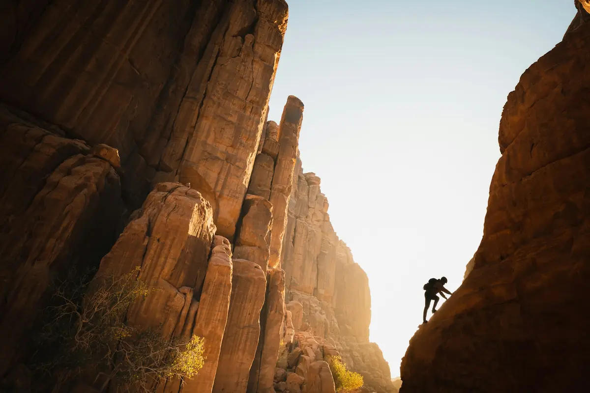 Climber silhouetted between tall sandstone towers at sunset
