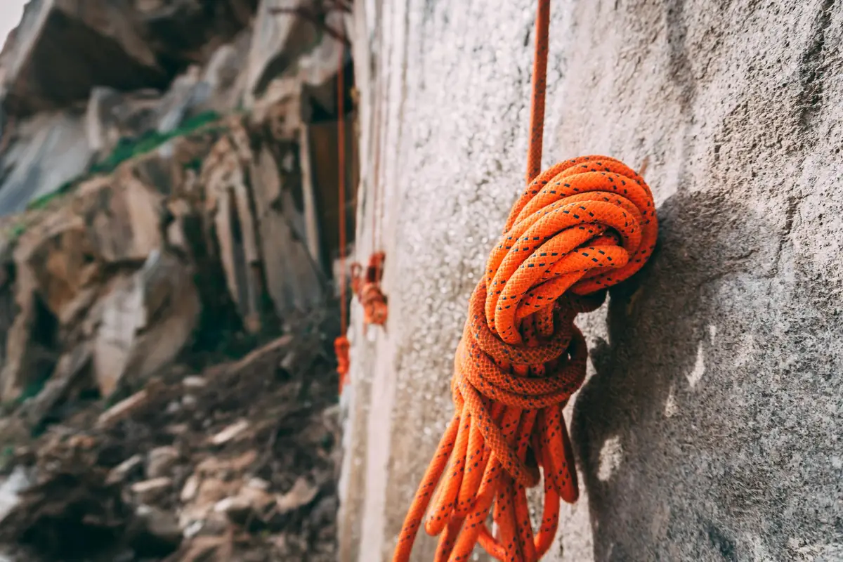 Orange climbing rope coiled against a rough granite wall